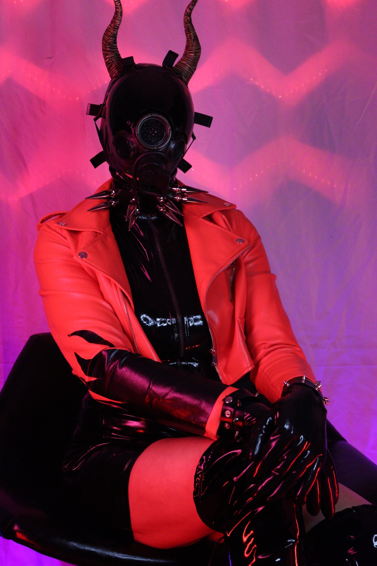 Picture of me, wearing a black latex top over a fishnet shirt, long black latex gloves and black latex skirt with a read streak. Also, I'm wearing a thigh-high black vinyl boots, a gas mask and a pair of horns.